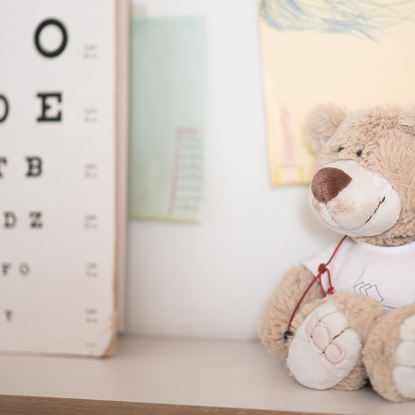 Teddybär mit Spielzeugstethoskop in einem Untersuchungsraum